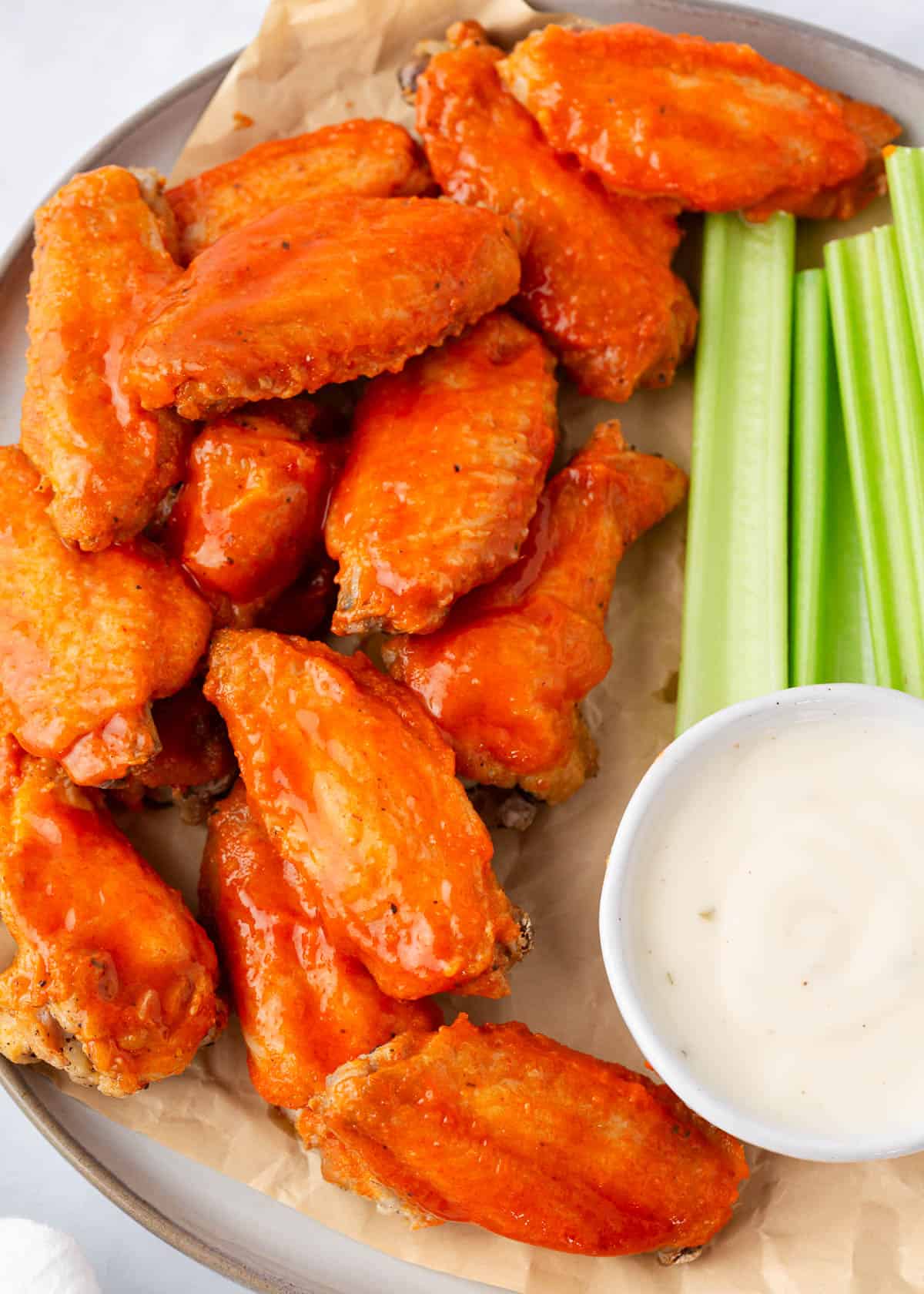 Crispy fried chicken wings with celery sticks and white dipping sauce on plate