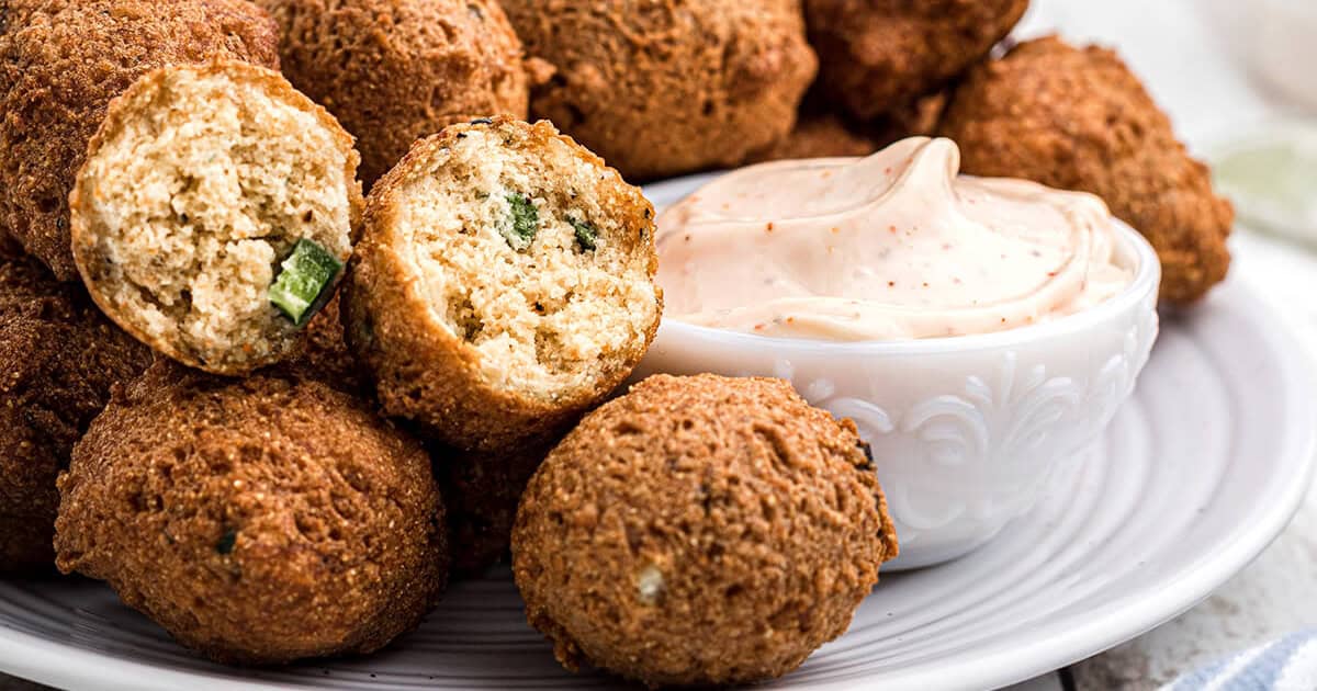 Fried meatballs with fresh herbs on white plate with creamy dipping sauce